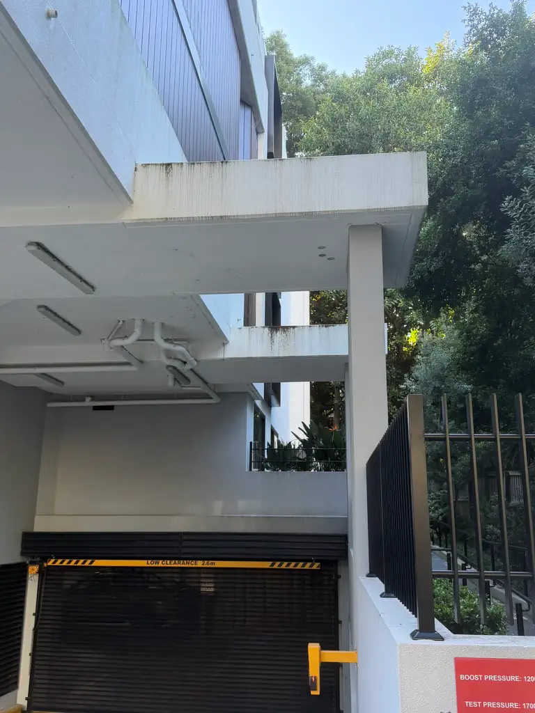 Car park entry with black mould streaks along the white soffit edge and render