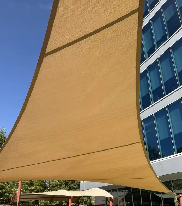 The same shade sail after soft washing, an even sand colour with the mould gone