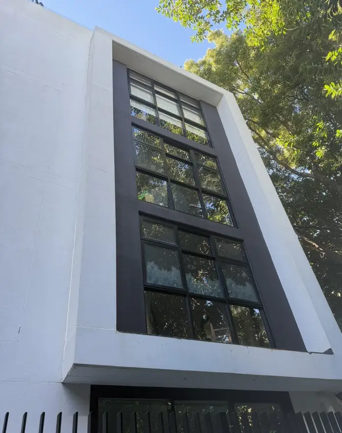 The same four-storey rendered building after soft washing, with clean sills and render