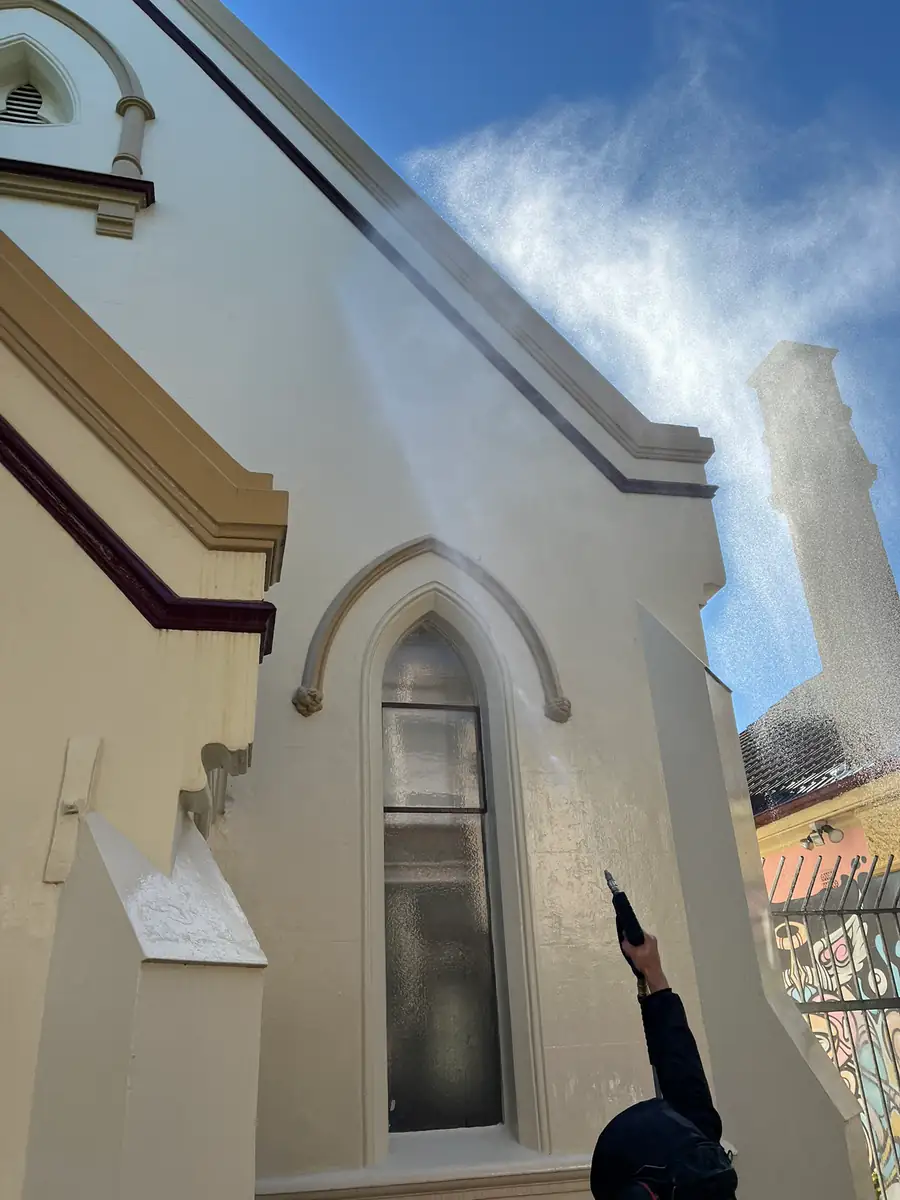 A Clean Haven operator soft washing the render of a heritage church