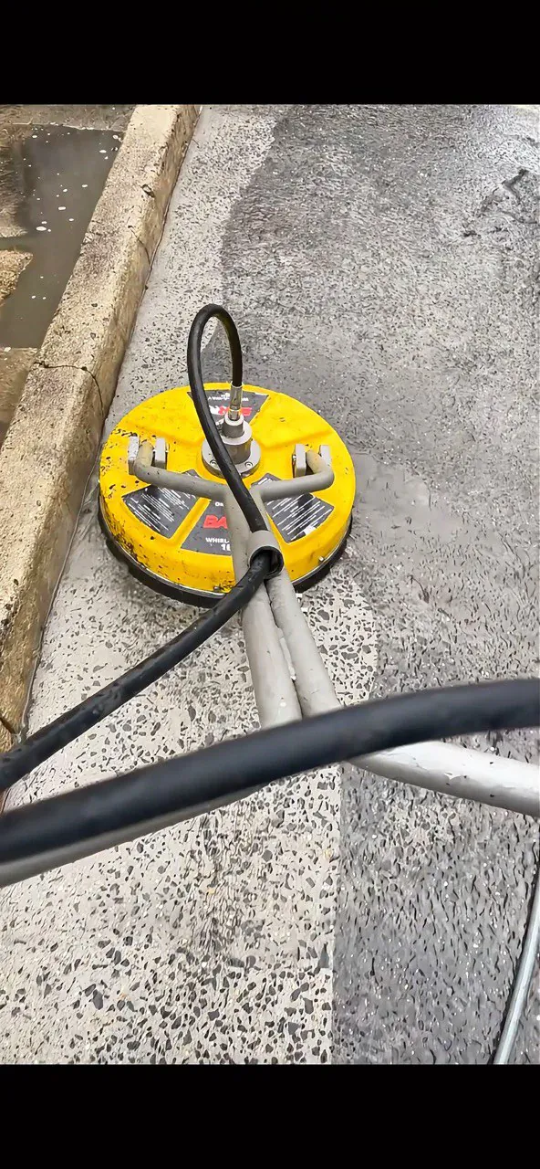 A surface cleaner pressure washing concrete, leaving a clean strip behind it