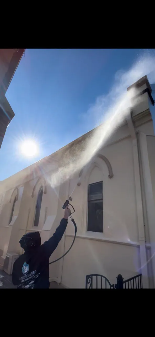 Soft wash solution being sprayed onto a rendered house facade